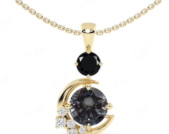 May include: A gold pendant necklace with a crescent moon design featuring a dark gray gemstone surrounded by smaller white gemstones. A black gemstone is suspended above the moon.
