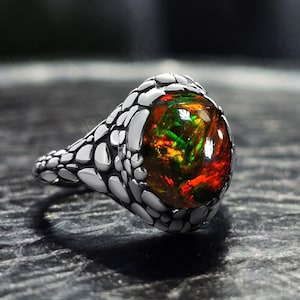 Puede incluir: Un anillo de plata con una gran piedra de ópalo redonda multicolor engastada en un diseño texturizado y escamoso.