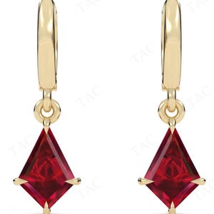 May include: A pair of gold hoop earrings with a dangling red gemstone. The gemstone is a square with pointed corners.