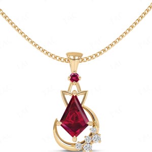 May include: A gold necklace with a pendant featuring a large, red, faceted gemstone surrounded by smaller, clear gemstones. The pendant is in the shape of a crescent moon with a stylized floral design.