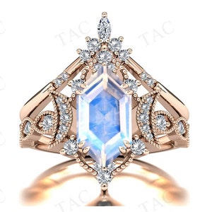 May include: A rose gold ring with a large, octagonal moonstone center stone. The ring is set with smaller diamonds in a delicate, floral design.