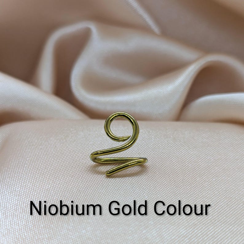 K&ouml;nnte beinhalten: Ein goldfarbener Ohrring aus Niob mit einem durchgehenden Drahtdesign, das oben eine Spirale und eine geschwungene Basis bildet. Das Metall hat eine glatte, polierte Oberfl&auml;che. Der Text Niobium Gold Colour ist unten im Bild aufgedruckt.