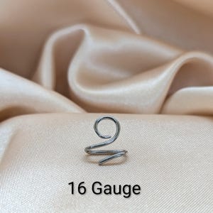 K&ouml;nnte beinhalten: Ein silberfarbener Ohrring aus Metall mit einem Spiraldesign, das oben eine einzelne Schlaufe und ein spitz zulaufendes Ende aufweist. Das St&uuml;ck ist deutlich mit dem Text 16 Gauge beschriftet, was die Dicke angibt, und besteht aus glattem Draht.