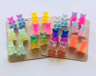 May include: A set of 18 gummy bear earrings in various colors, including pink, blue, green, orange, and yellow. The earrings are displayed on two brown cards.