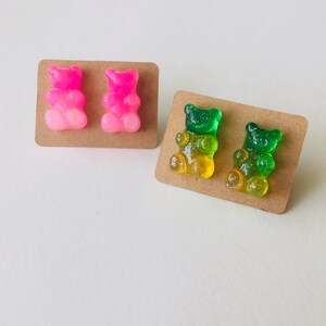 May include: Two pairs of gummy bear earrings. One pair is pink and the other is green and yellow.