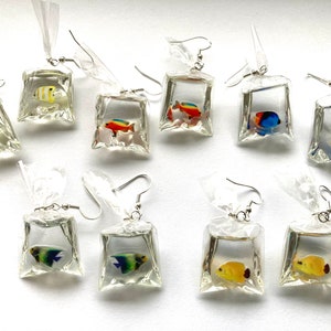 May include: Ten pairs of dangle earrings featuring colorful fish inside clear plastic bag charms. The charms are silver and have a silver hook.
