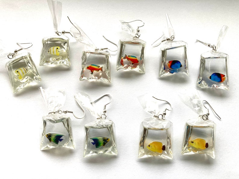 May include: Ten pairs of dangle earrings featuring colorful fish inside clear plastic bag charms. The charms are silver and have a silver hook.