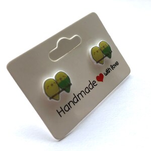 May include: A pair of green and yellow bird earrings on a white card with the text "Handmade with love".