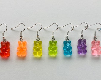 May include: A set of 10 gummy bear dangle earrings in various colors, including white, red, orange, yellow, green, blue, purple, pink, and black.