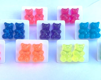 May include: A set of 10 pairs of gummy bear earrings in various colors, including red, orange, yellow, green, blue, and purple. Each pair is displayed on a white card.