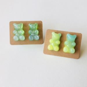 May include: Two pairs of gummy bear earrings. One pair is green and the other is yellow and blue.