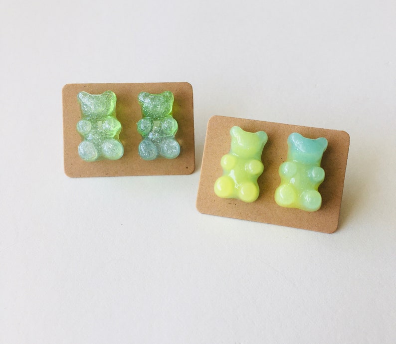 May include: Two pairs of gummy bear earrings. One pair is green and the other is yellow and blue.