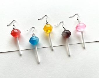 May include: Five pairs of dangle earrings featuring colourful lollipop charms. The lollipops are red, yellow, blue, brown and pink.