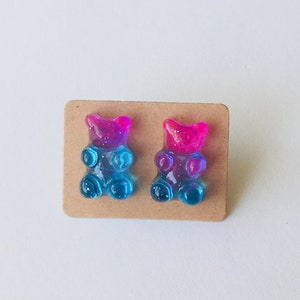 May include: A pair of gummy bear earrings, one pink and blue, the other blue and pink.