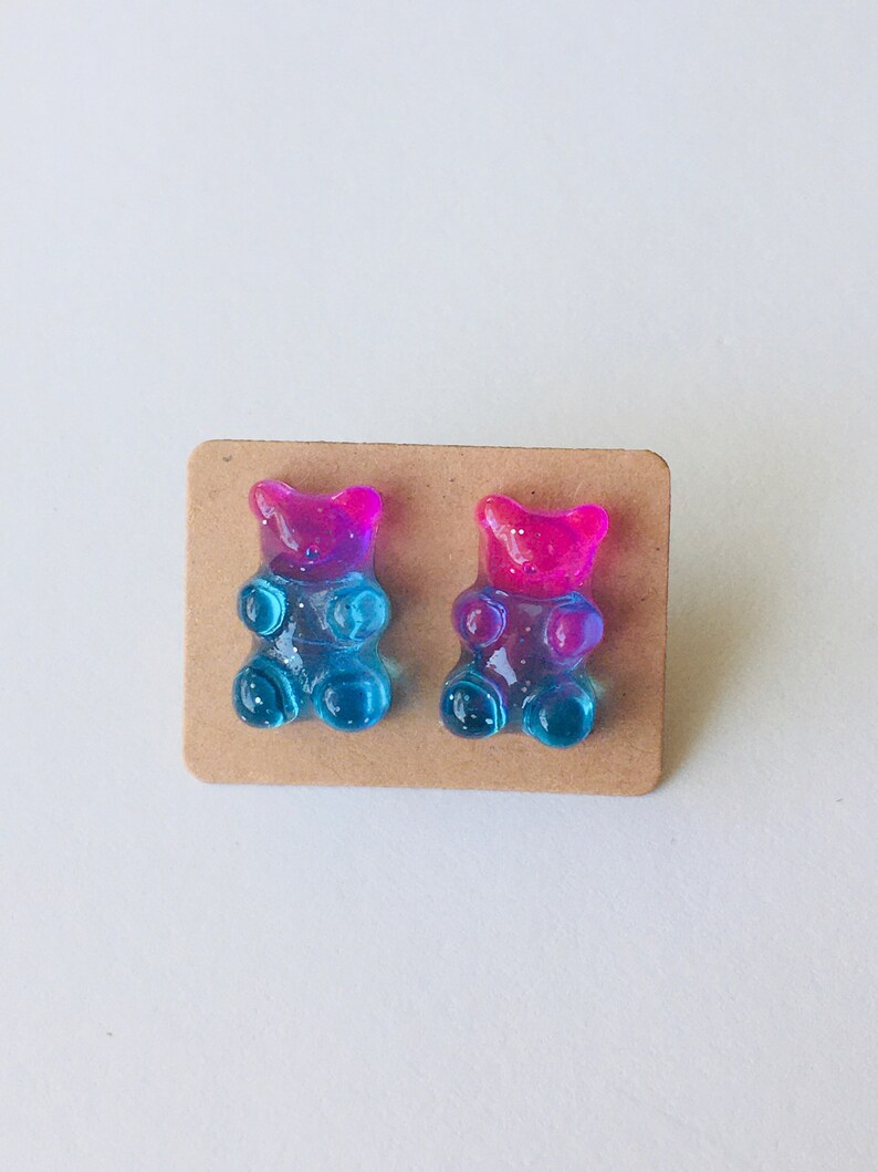 May include: A pair of gummy bear earrings, one pink and blue, the other blue and pink.