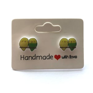 May include: A pair of green and yellow bird stud earrings on a white card with the text "Handmade with love".