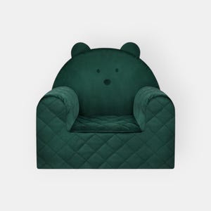 Puede incluir: Un sillón infantil de terciopelo verde con diseño acolchado y orejas de oso.