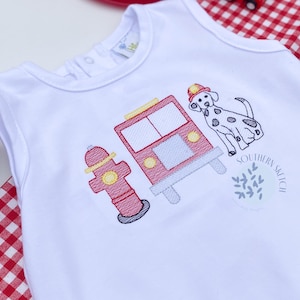 May include: White sleeveless onesie with an embroidered fire truck, fire hydrant, and dalmatian dog. The text "Southern Stitch" is embroidered on the onesie.