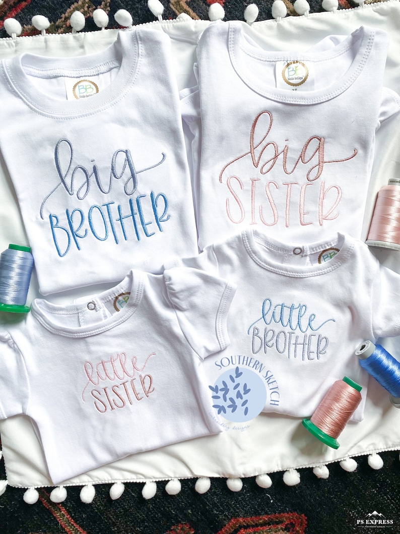 May include: Four white t-shirts with embroidered text. Two shirts say "big brother" and "big sister" in pink and blue script. Two shirts say "little sister" and "little brother" in pink and blue script.