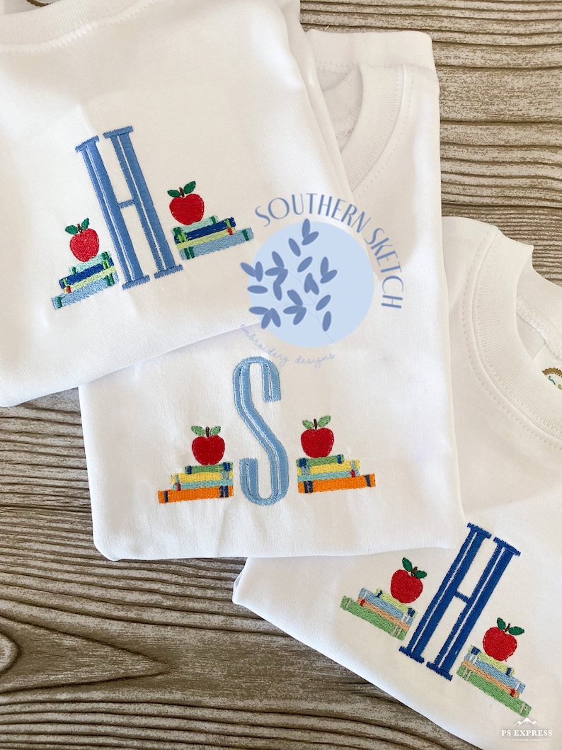 Puede incluir: Tres camisetas blancas con letras bordadas y pilas de libros con manzanas en la parte superior. Las letras son H, S y H. Las camisetas est&aacute;n apiladas una encima de la otra. El texto "SOUTHERN SKETCH" est&aacute; bordado en la camiseta superior.