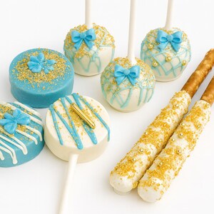 Pu&ograve; includere: Un assortimento di dolcetti decorati, tra cui cake pops blu e bianchi con fiocchi, biscotti glassati blu e bastoncini di pretzel ricoperti di cioccolato bianco e zuccherini dorati. Una presentazione festosa ed elegante.
