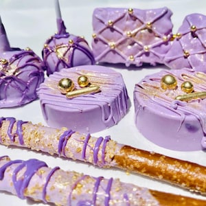 May include: Purple and gold decorated chocolate covered pretzels, cake pops, and cookies. The treats are decorated with gold sprinkles, edible gold balls, and gold lines.