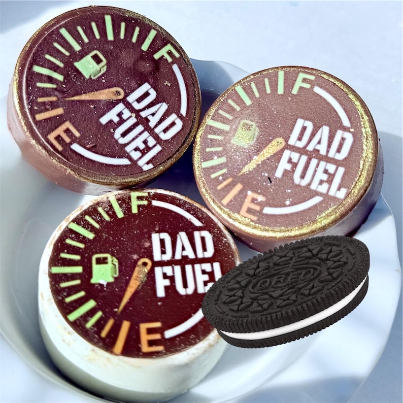 May include: A plate holds three round chocolate treats with a gauge design and the words "DAD FUEL" in white. The gauge shows a fuel tank and needle. An Oreo cookie sits next to the treats.