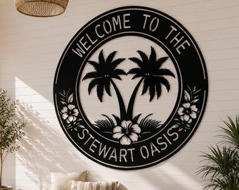 Könnte beinhalten: Ein schwarzes Metall-Wandkunstwerk mit den Worten "WELCOME TO THE STEWART OASIS" in einem kreisförmigen Design. Die Kunst zeigt Palmen und florale Akzente, montiert an einer weißen Wand über einer Holzbank.