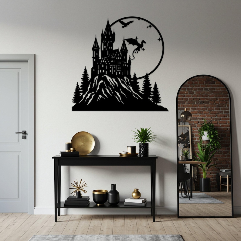 Pode incluir: Arte de parede em metal preto retratando um castelo em uma montanha, com um drag&atilde;o e p&aacute;ssaros voando ao redor de uma lua circular. A obra de arte &eacute; montada em uma parede branca.