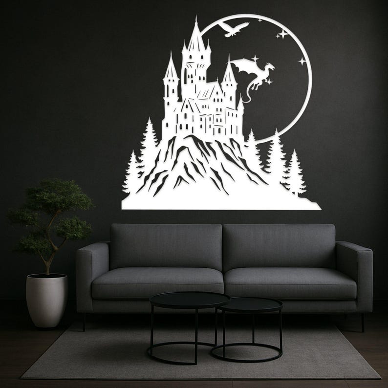 Pode incluir: Arte de parede em metal branco que retrata um castelo numa montanha, com um drag&atilde;o, p&aacute;ssaros e estrelas contra um fundo circular. O castelo apresenta m&uacute;ltiplas torres e &eacute; rodeado por &aacute;rvores estilizadas. A obra de arte &eacute; montada numa parede escura acima de um sof&aacute; cinzento.