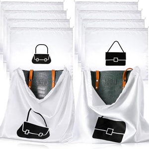 May include: White satin dust bags with black purse illustrations. The bags are designed to protect handbags. A dark green handbag with brown straps is partially visible, inside one of the bags. The bags have a drawstring closure.