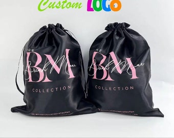 May include: Two black satin drawstring bags with the text "The Brush Mama Collection" and a pink logo of "BM" printed on them.