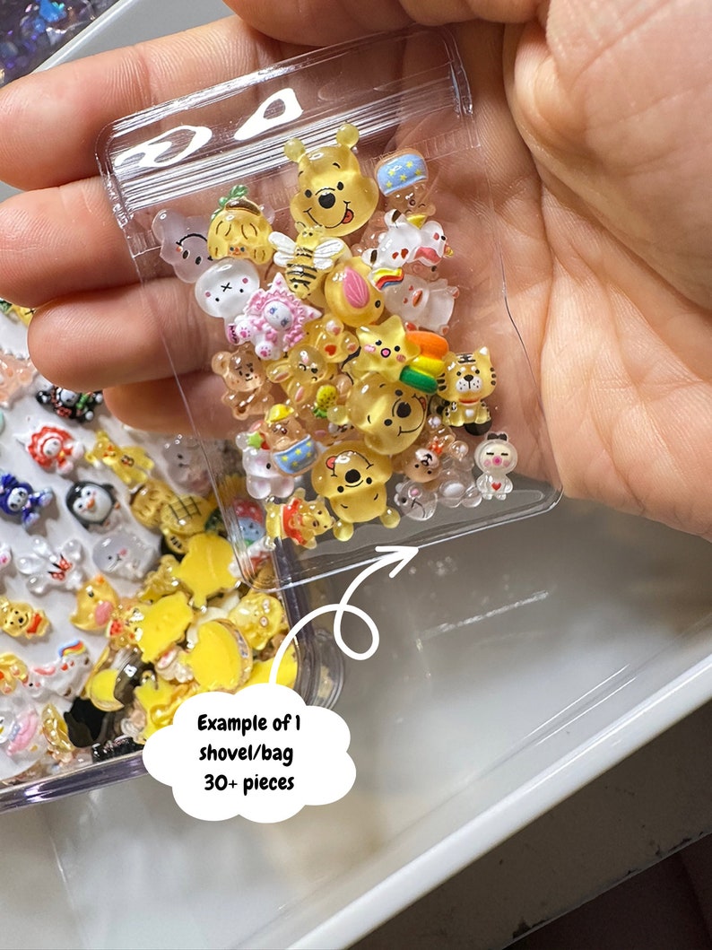 Pu&ograve; includere: Un sacchetto di plastica trasparente pieno di piccole figurine di personaggi dei cartoni animati colorati. Il sacchetto &egrave; etichettato "Esempio di 1 pala/sacchetto 30+ pezzi".