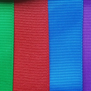 Pode incluir: Seis rolos de fita de diferentes cores, da esquerda para a direita: laranja, verde, vermelho, azul, roxo e cinza claro.