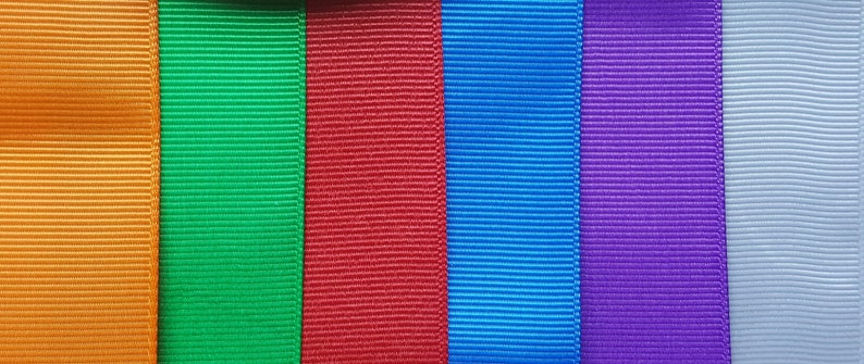 Pode incluir: Seis rolos de fita de diferentes cores, da esquerda para a direita: laranja, verde, vermelho, azul, roxo e cinza claro.