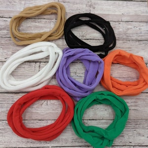 Pode incluir: Um conjunto de oito el&aacute;sticos de cabelo em v&aacute;rias cores, incluindo preto, branco, castanho, roxo, laranja, vermelho e verde. Os el&aacute;sticos de cabelo s&atilde;o feitos de um tecido macio e el&aacute;stico.