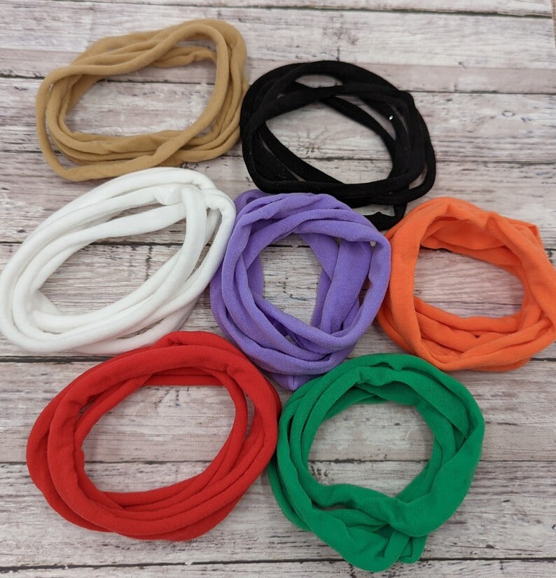 Pode incluir: Um conjunto de oito el&aacute;sticos de cabelo em v&aacute;rias cores, incluindo preto, branco, castanho, roxo, laranja, vermelho e verde. Os el&aacute;sticos de cabelo s&atilde;o feitos de um tecido macio e el&aacute;stico.
