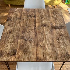 May include: A rustic wooden table top with a natural wood grain finish. The table top is brown with a slightly orange hue. The table top is made of reclaimed wood.