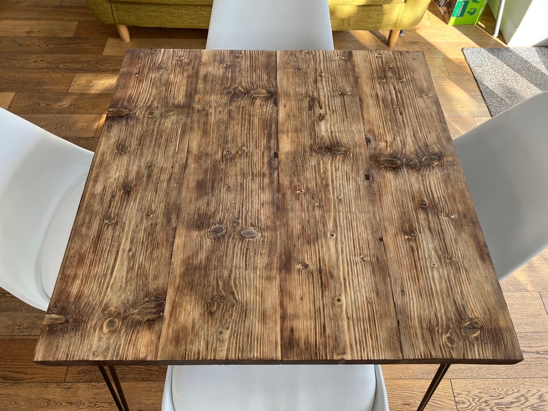 May include: A rustic wooden table top with a natural wood grain finish. The table top is brown with a slightly orange hue. The table top is made of reclaimed wood.