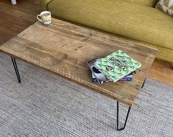 Mesa de centro artesanal de madera reciclada: mesa rústica industrial con forma de tablón de andamio y patas de horquilla de colores.