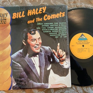 May include: A vinyl record album cover featuring Bill Haley and the Comets. The cover is yellow and gold with a picture of Bill Haley in a black suit and bow tie. The album title is "Everest Golden Greats Bill Haley and the Comets". The album includes songs like "Rock Around the Clock", "Shake, Rattle & Roll", "See You Later Alligator", "Rock-A-Beat'n Boogie", "Saints Rock 'N Roll", "Razzle Dazzle", "Rock the Joint", and "Rip It Up".