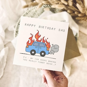 Peut inclure: Une carte de vœux carrée avec le texte HAPPY BIRTHDAY DAD en haut. En dessous, une illustration de dessin animé d'une voiture bleu clair en proie à des flammes orange et rouges avec de la fumée d'échappement grise. Le texte P.S - MY CAR KEEPS MAKING THIS REALLY FUNNY NOISE...?