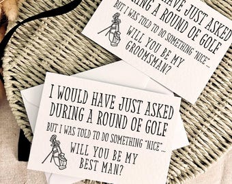 May include: Two white cards with black text, asking "Will you be my Groomsman?" and "Will you be my Best Man?" with a golf bag illustration. The cards are on a woven basket.