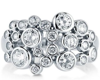 May include: A silver ring with a cluster of round, clear gemstones set in a bubble-like design.