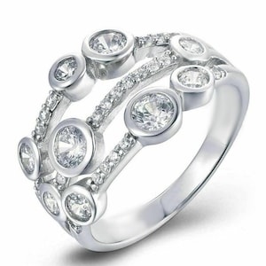 Puede incluir: Un anillo de plata con múltiples piedras redondas transparentes engastadas en una banda con un diseño delicado.