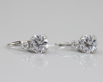 May include: A pair of silver earrings with a large round clear stone and two smaller clear stones on each earring.