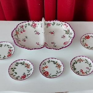 Jeden talerz na cukierki i pięć małych talerzyków na amuse-bouche. Biała porcelana z fioletowymi zdobieniami i kwiatowymi girlandami. Vintage z lat 40. XX wieku.