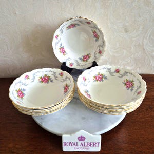 Puede incluir: Juego de seis cuencos de sopa blancos con un patrón floral en tonos de rosa, azul y verde. Los cuencos tienen un borde dorado y están apilados sobre una superficie de mármol. Los cuencos están hechos por Royal Albert, Inglaterra.