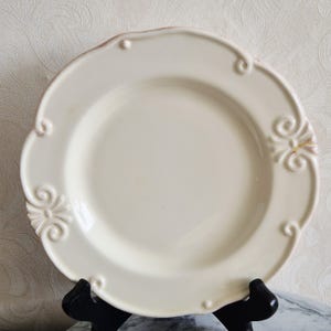 Cream-colored cake plate made of earthenware from Tout à table, fabrique and St. Jean Cap Ferrat, decorated with fleur-de-lys or French lily.