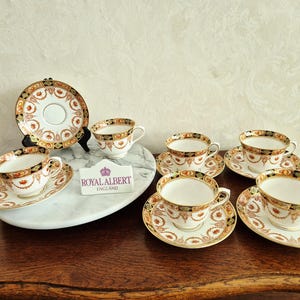 Royal Albert Kopp och fat, Crown China England "namnlös". Röd med svart mönster, rikt dekorerad med guld, Devon Black 1927-1935